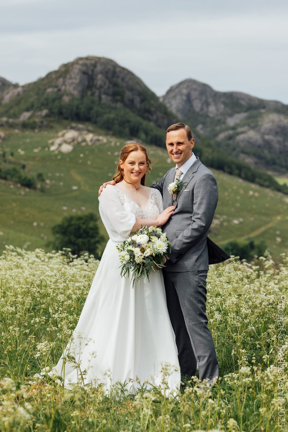 Grete og Thomas i blomstereng med fjell i bakgrunnen