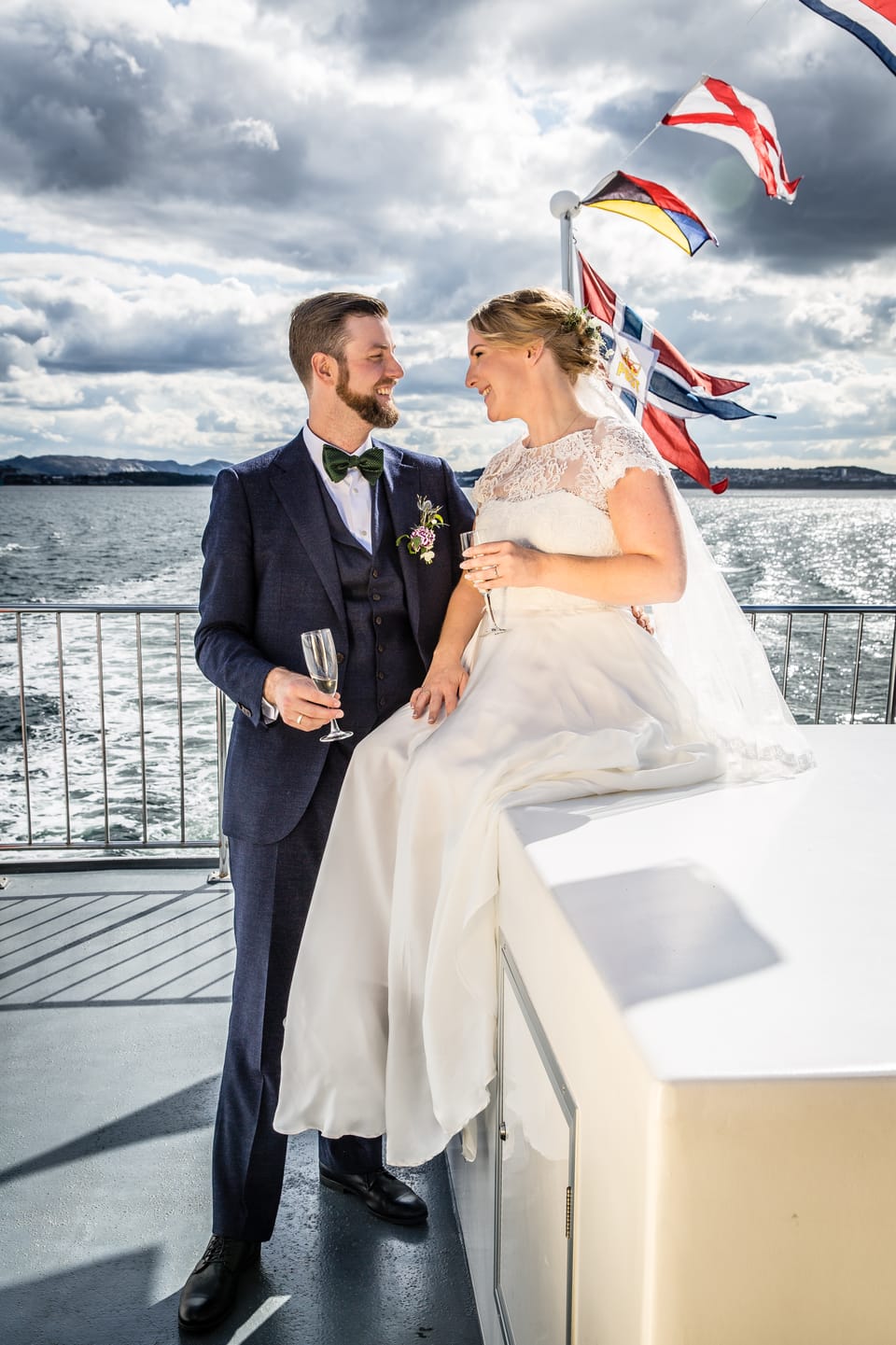 Ingrid og Sander med champagne på båtdekk, norske flagg vaier i vinden