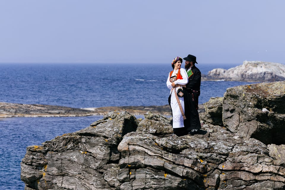 Silje og Jamie i bunad på klippe mot åpent hav